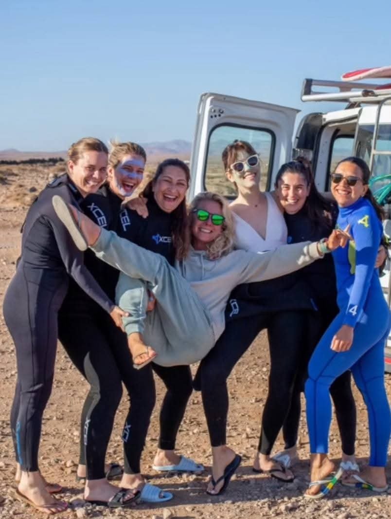 Group of smiling surf students in wetsuits after a surf lesson in Corralejo, Fuerteventura