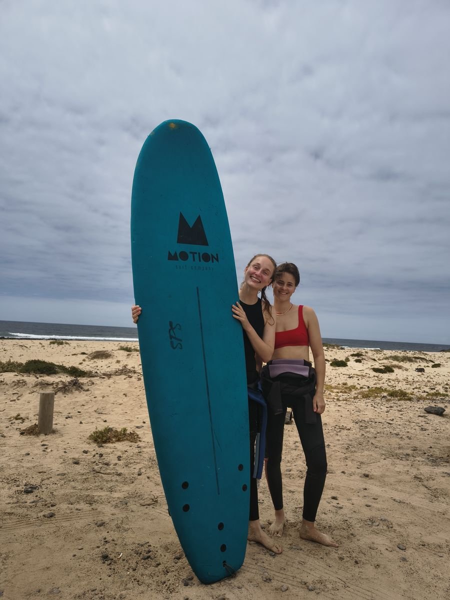 Two surfers with a surfboard on the beach in Fuerteventura