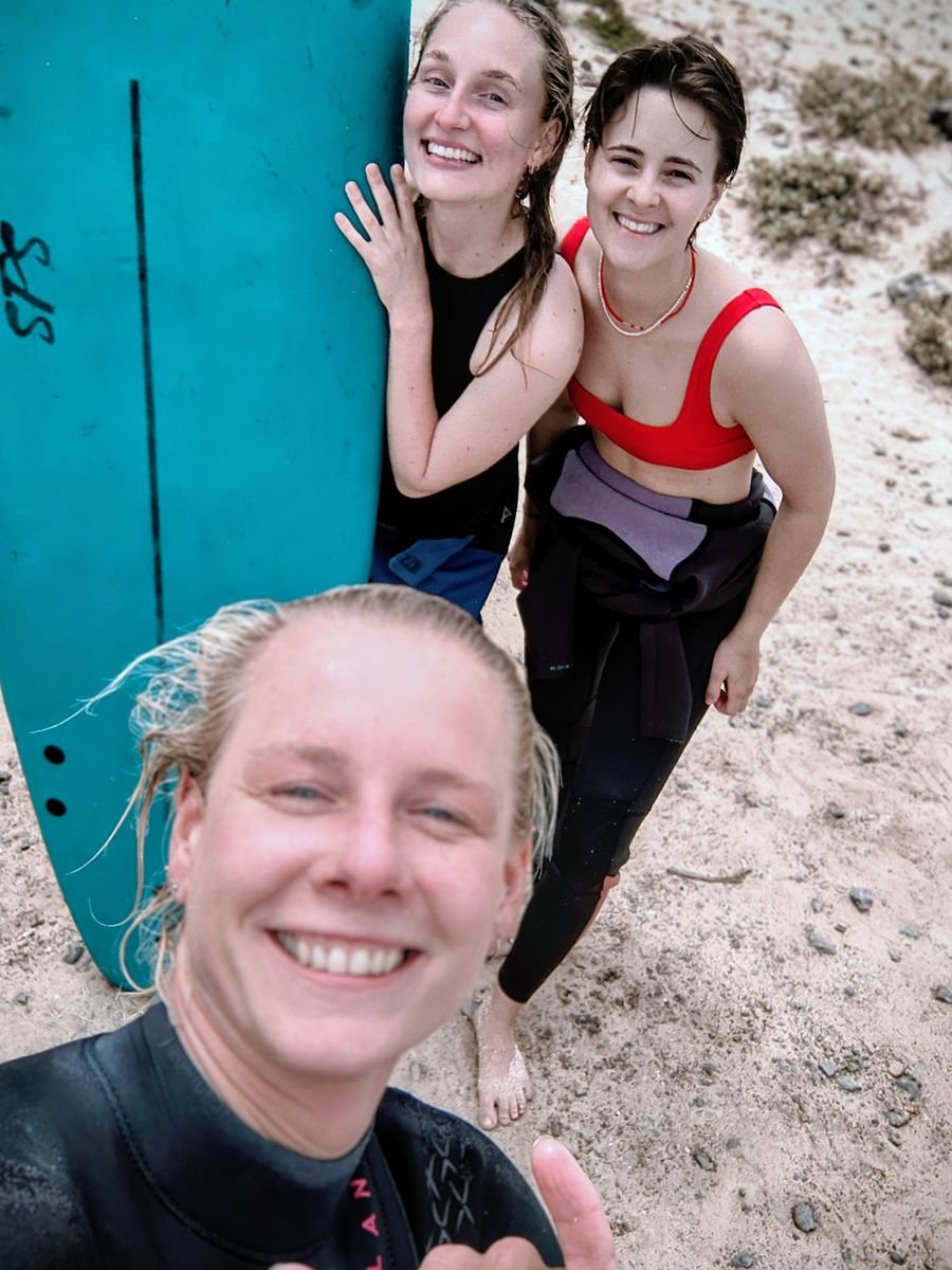 Smiling surf students with their boards after a lesson with Pure Waves Surf