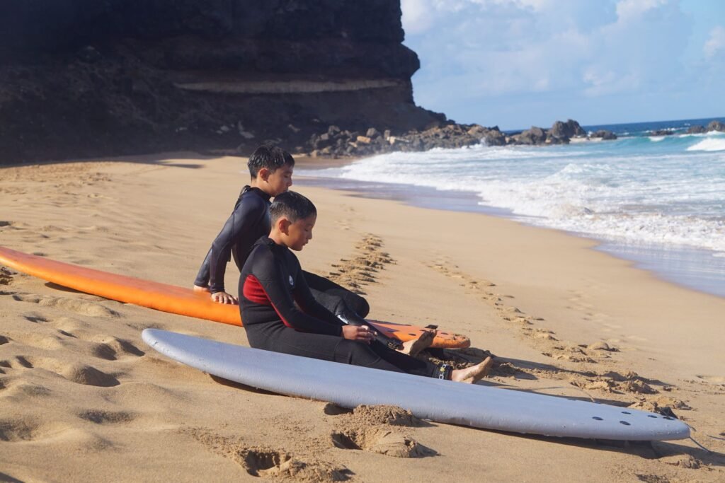 Kids practising the pop-up on surfboards on the beach during a surf lesson