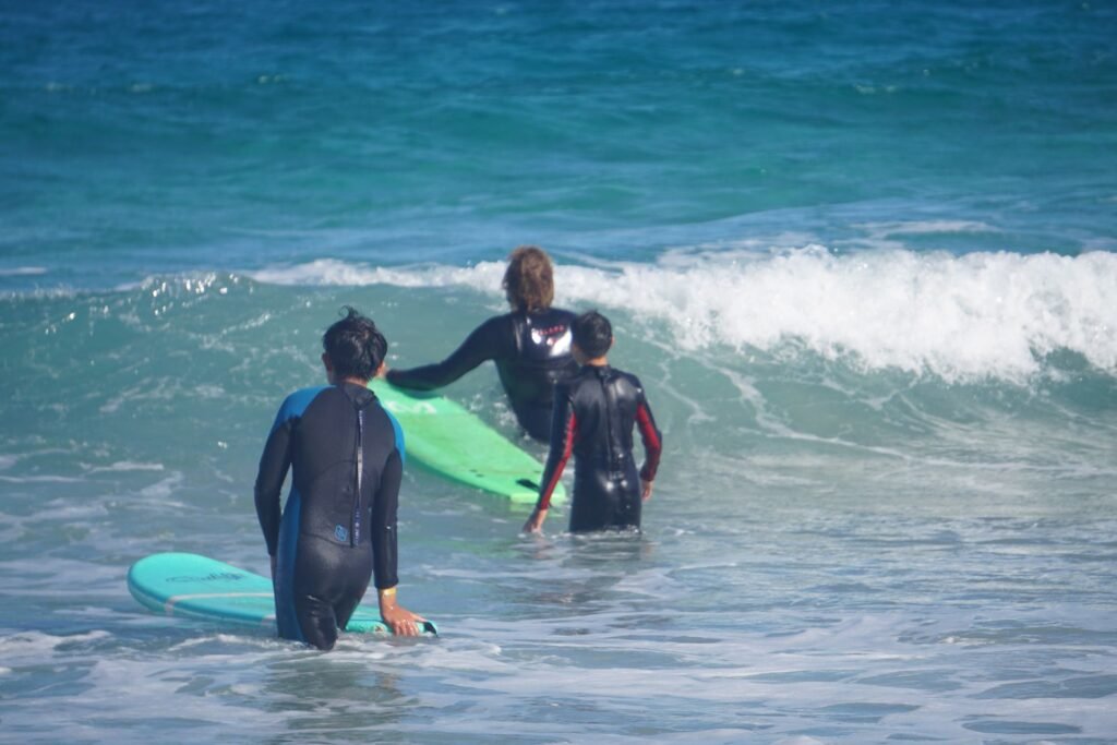 Surf instructor helping a student into the whitewater during a beginner lesson