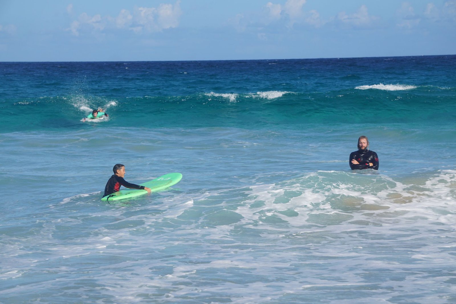 Beginner surfers paddling in turquoise water during a surf lesson, Fuerteventura