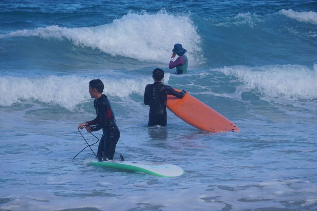 Students walking their surfboards through the whitewater during a beginner lesson