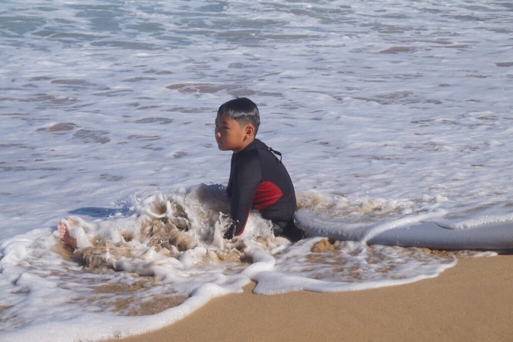 Young surfer sitting in the whitewater during a surf lesson in Fuerteventura