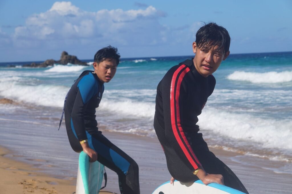 Two surf students with their boards on the beach after a lesson