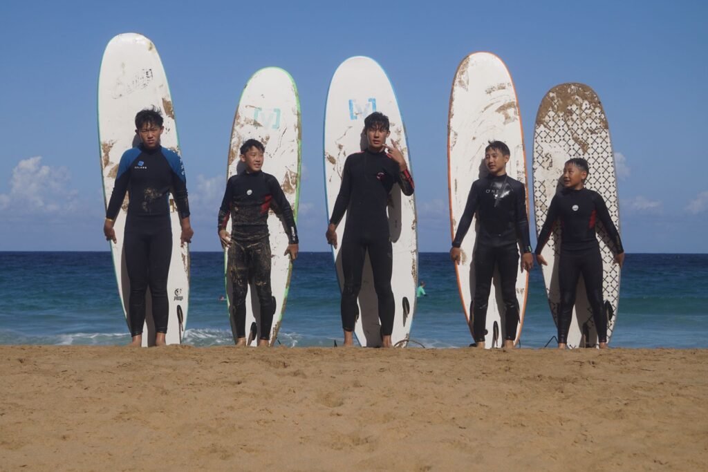 Surf group posing in front of their surfboards on the beach in Fuerteventura