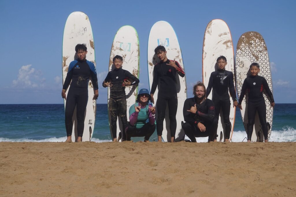 Pure Waves Surf group photo with instructors and students in front of surfboards